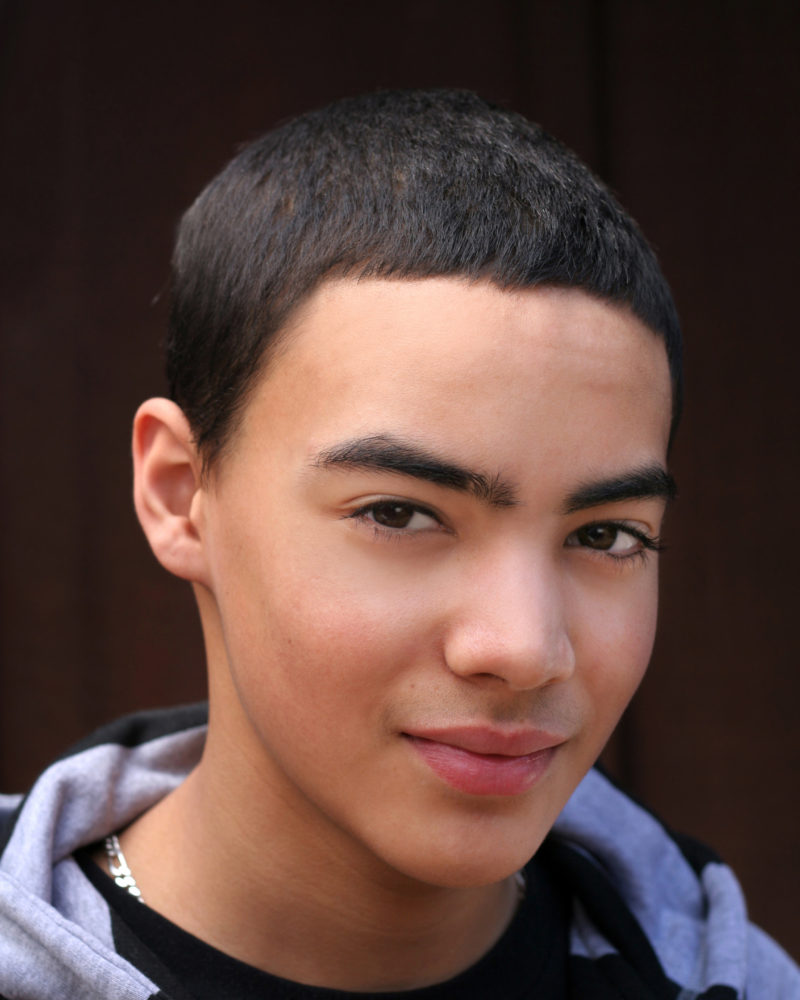 Teen Boy Portrait of multi-cultural teen boy with slight smile against dark background